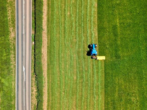 Blue tractor seen from above on green cropland.